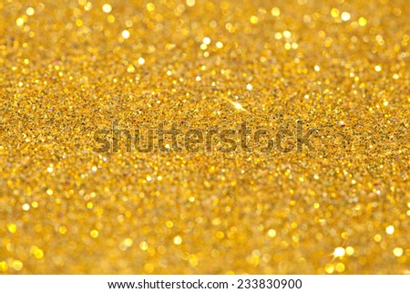Abstract gold glitter festive background texture with shining glitter stars. Full frame yellow color christmas detail with blurred areas. Artistic colorful background drop frame.