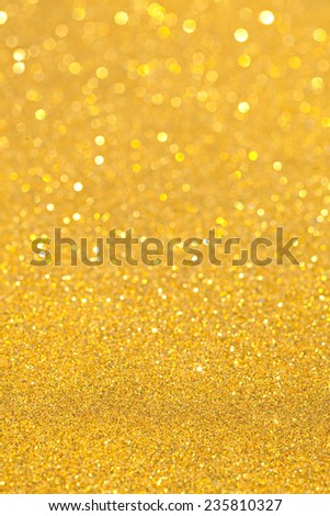 Abstract gold glitter festive background texture with shining glitter stars. Full frame yellow color christmas detail with blurred areas. Artistic colorful background drop frame space.
