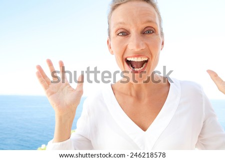 Close up beauty portrait of happy and joyful woman with a fun surprise and carefree expression of joy against blue sky and sea background. Feelings and emotions in lifestyle. Gestures and expressions.