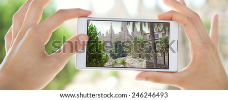 Panoramic close up detail view of young tourist woman hands holding a smartphone mobile cell device, taking pictures of a monument while sightseeing on a holiday trip. Travel and technology outdoors.