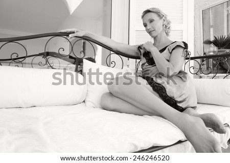 Black and white portrait of beautiful senior woman lounging on a day bed outdoors, relaxing at home while wearing a silk lingerie dress being thoughtful, outdoors. Summer beauty middle age lifestyle.