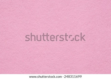 Close up detail view of a pink piece of textured felt fabric with rough touch. Full frame background texture pattern of art and stationery material in magenta color.