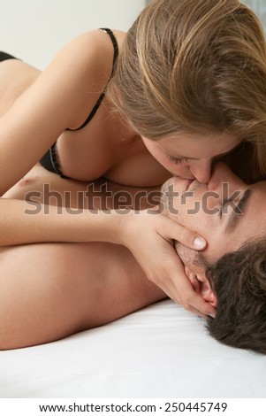Close up of a young and attractive couple kissing on the lips, being intimate and having sex in a hotel bedroom, wearing underwear. Relationships, sex and emotions. Lifestyle, home interior.