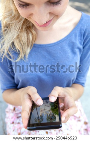 Close up view of young attractive tourist woman holding and using a touch screen smartphone mobile device, flicking through holiday pictures on vacation. Travel and technology networking outdoors.