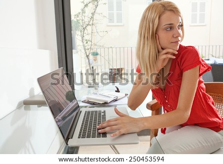Portrait of a young professional woman being thoughtful in her home office space, turning away. Student girl using a laptop computer at her home work desk. Lifestyle and technology, interior.