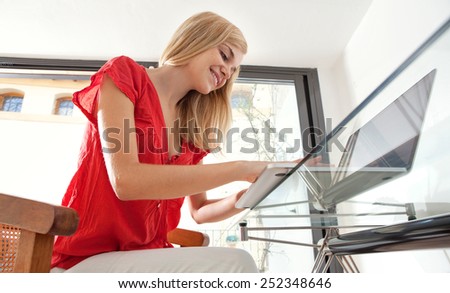 Portrait of a young professional woman smiling in her home office space, typing and working on line. Student girl using a laptop computer at her home work desk. Lifestyle and technology, interior.