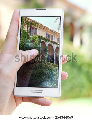 Close up detail of a young tourist woman hands holding and using a touch screen smartphone device, to take holiday pictures of a building on vacation. Travel and lifestyle technology outdoors.