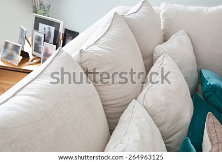 Still life interior design home living room with comfortable white sofa with cushions, and family picture frames in a home interior, close up detail. Aspirational home family room, indoors lifestyle.