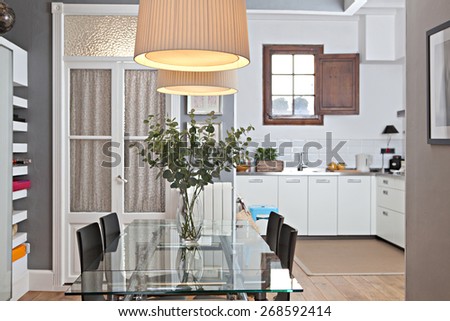 Still life interior home dining room and kitchen with a comfortable and welcoming glass table in a spacious wooden floors house. Aspirational home dining room and kitchen, indoors living lifestyle.