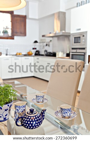 Still life interior design home dining room and kitchen view with a teapot set serving of hot drinking tea in a spacious stylish house. Aspirational home dining room and kitchen, relaxing lifestyle.