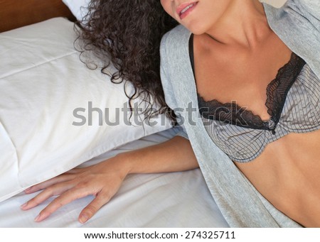 Faceless body view of beautiful young exotic woman wearing sexy lingerie, lounging on a bed at home, interior space. Healthy wellness and well being living aspirational lifestyle, bedroom indoors.