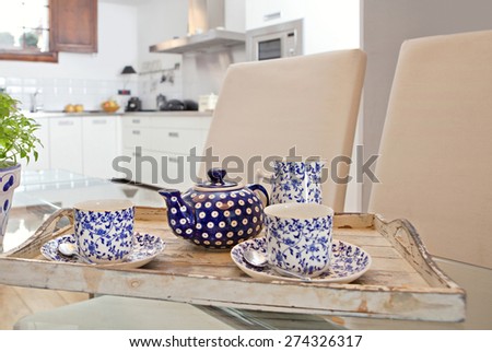 Still life interior home dining room and kitchen view with serving set of hot tea on a glass table in a spacious stylish house. Aspirational dining room and kitchen, relaxing and comforting lifestyle.