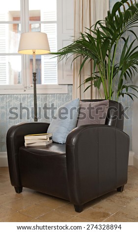 Still life interior design relaxing home reading room with comfortable quality leather armchair in a stylish house. Aspirational home room with cushions and lamp by a window, indoors living lifestyle.