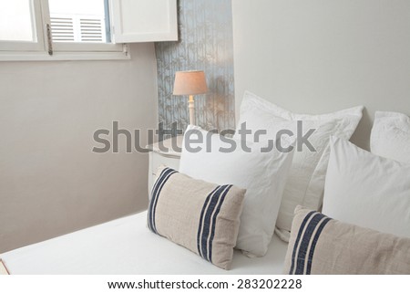 Still life view of comfortable luxury home bedroom with white and stripy pillows in a quality family home, interior design. Stylish bed in home room with a window and wallpaper with details, indoors.
