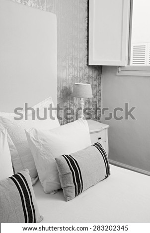 Black and white still life view of comfortable luxury home bedroom with white and stripy pillows in quality family home, interior design. Stylish aspirational bed in home room with a window, indoors.