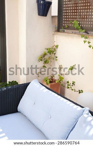 Still life view of a home outdoors living room and terrace garden sitting area with a comfortable wicker sofa, in a stylish house, indoors and outdoors. Empty space, aspirational lifestyle.