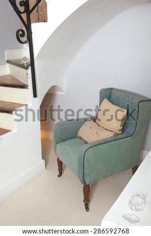 Still life home interior view of a traditional quality and luxurious wooden armchair in a living room with stairs, indoors. Elegant reading room with upholstery chair, empty space.