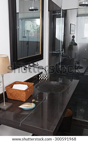 Still life view of a quality luxurious bathroom with a black marble elegant expensive sink and shower in an exclusive bachelor home, bath interior. Masculine hotel bathroom for travelers, indoors.