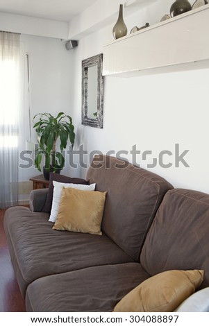 Still life view of a family home living room with a comfortable brown sofa with cushions in house interior. Home relaxing family room space, indoors. Furniture and furnishing in home living, indoors.