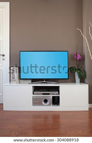 Still life view of a large home entertainment tv flat screen in a modern technology house, interior. Elegant luxurious home cinema smart flat screen television with a blue screen, stylish indoors.