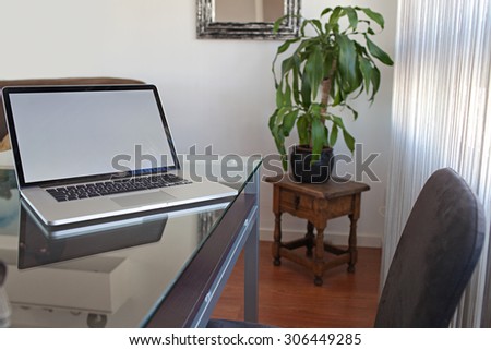 Still life view of an apartment living room with an open laptop on a professional glass desk workplace, house interior. Home office using technology, indoors. Working from home lifestyle.