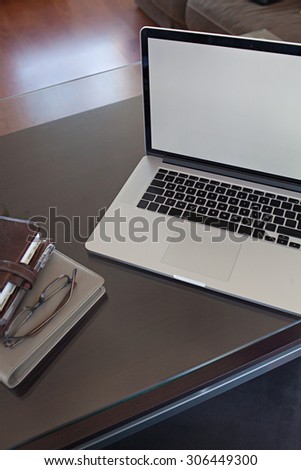 Still life view of a male office desk with an open laptop computer on a dark wooden table, professional office interior with paperwork. Professional workplace with reading glasses, technology indoors.