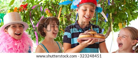 Panoramic portrait of group of children in fancy dresses at a colorful birthday party in bright home garden. Cake with candle, joyful expressions outdoors lifestyle. Kids activities and fun.