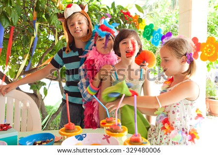 Group of children dressing up in fancy dresses at colorful birthday party in home garden with bright decorations, party food and with joyful expressions, outdoors lifestyle. Kids activities and fun.