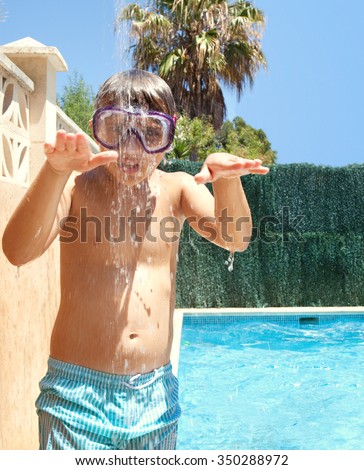Portrait of boy child under a shower having fun in swimming pool home garden on a sunny summer holiday, outdoors. Active kids lifestyle, pulling faces wearing diving mask, house exterior vacation.