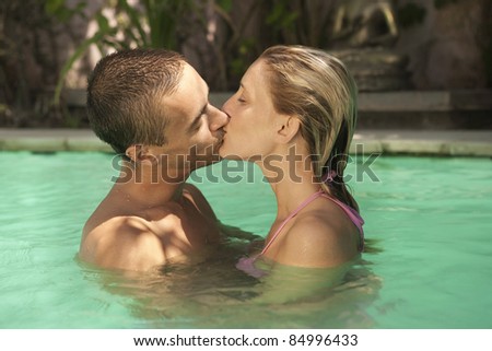 Couple kissing in a swimming pool, on vacation.