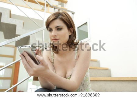 Young professional using a digital organizer while sitting in a modern stairwell.