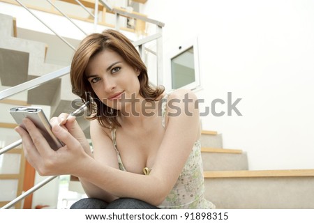Young professional using a digital organizer while sitting in a modern stairwell.