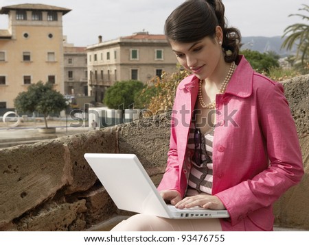Young sophisticated woman using a laptop outdoors.