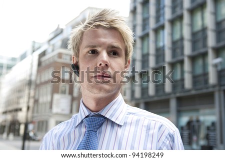 Young businessman using a hands free device to speak on the phone, outdoors.