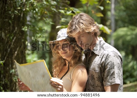 Couple reading a map in a tropical forest.