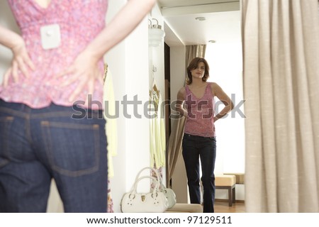 Young woman trying on an outfit in a fashion store\'s fitting room.