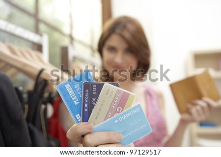 Young woman showing off her credit cards while standing in a fashion store.