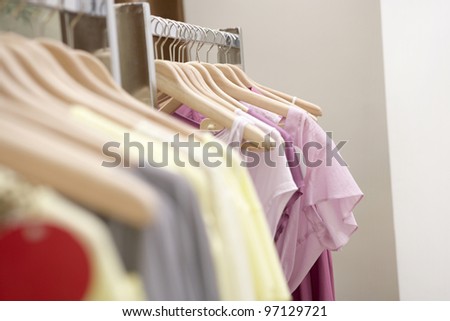 Detail of clothes hanging on wooden hangers in a fashion store.