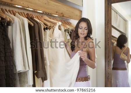 Young attractive woman looking at clothes in a fashion store.