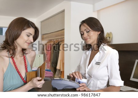 Client making payment at store\'s till with credit card.