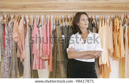 Young store attendant standing proudly by a line of clothes in a fashion store.