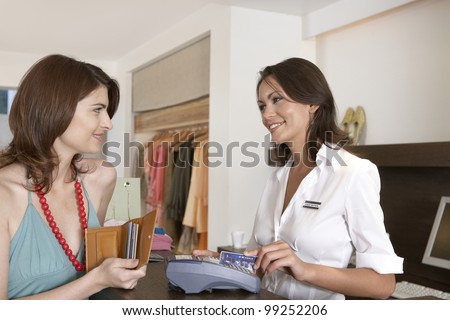 Client making payment at store\'s till with credit card.