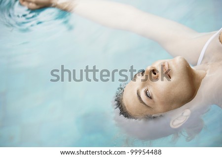 Overhead view of an attractive young woman floating on blue water.
