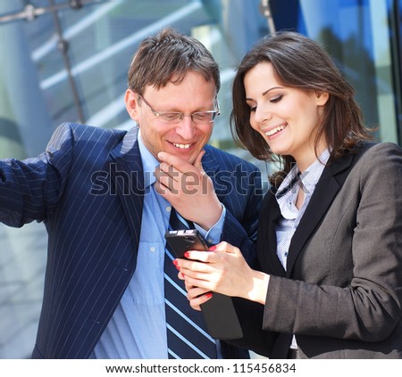 Conceptual photo of businessman showing something in the smartphone to his female assistant