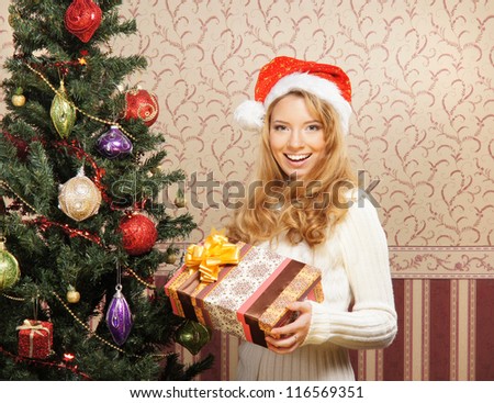 Beautiful teenager girl with the present near the Christmas tree