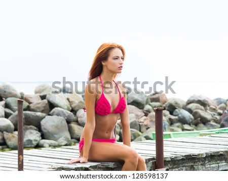 Young sexy woman in swimsuit relaxing on the pier