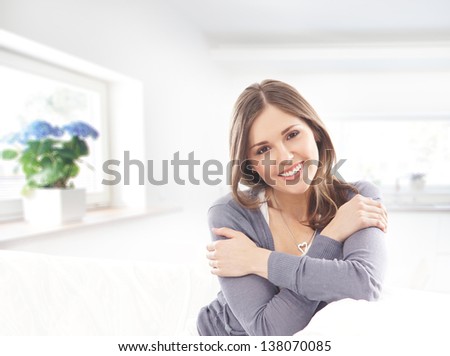 Beautiful and happy young woman sitting on the sofa over the kitchen background