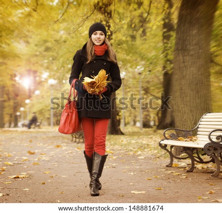 Beautiful and happy young woman with a bouquet of autumn leaves