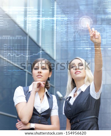 Two young and attractive business women working with a futuristic virtual display (business people in futuristic interface concept)