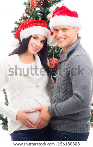 Young pregnant woman and happy father decorating Christmas tree isolated on white